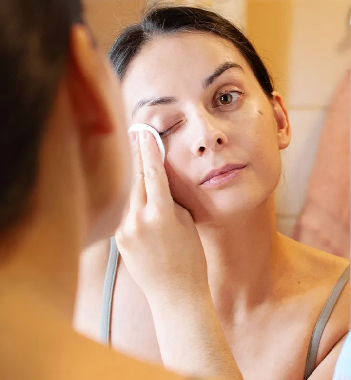 Woman safely removing false lashes using makeup remover at home.