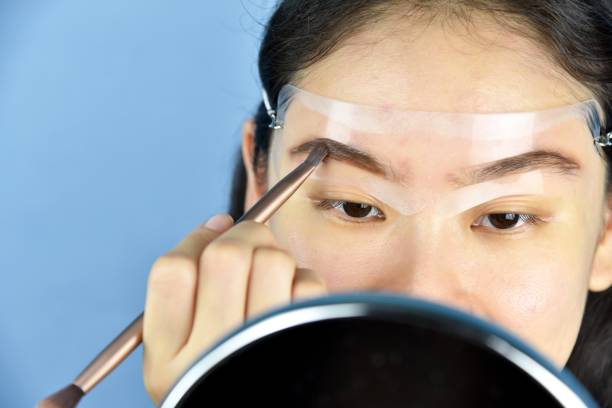 Using eyebrow stencil for even brow shaping.
