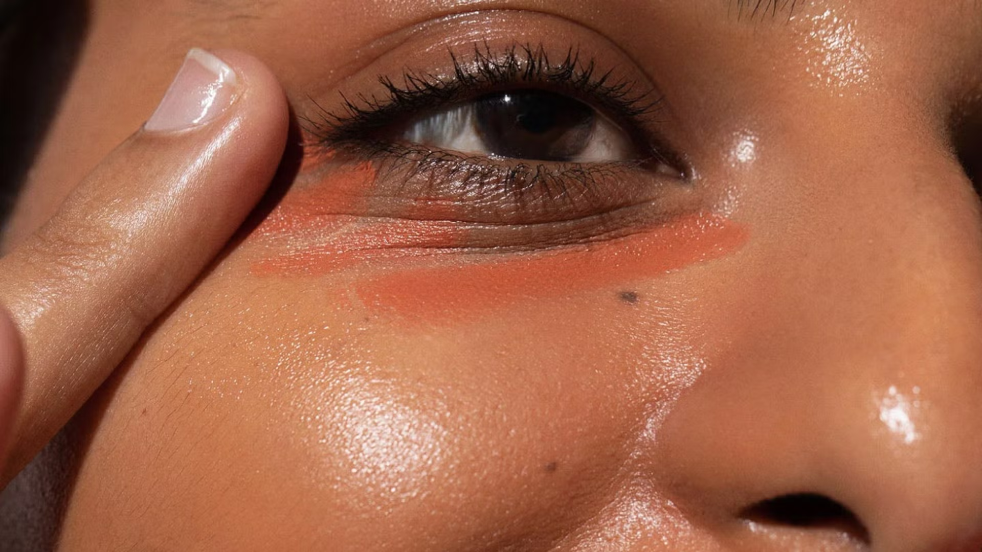  Applying orange color correctors on under-eye area.